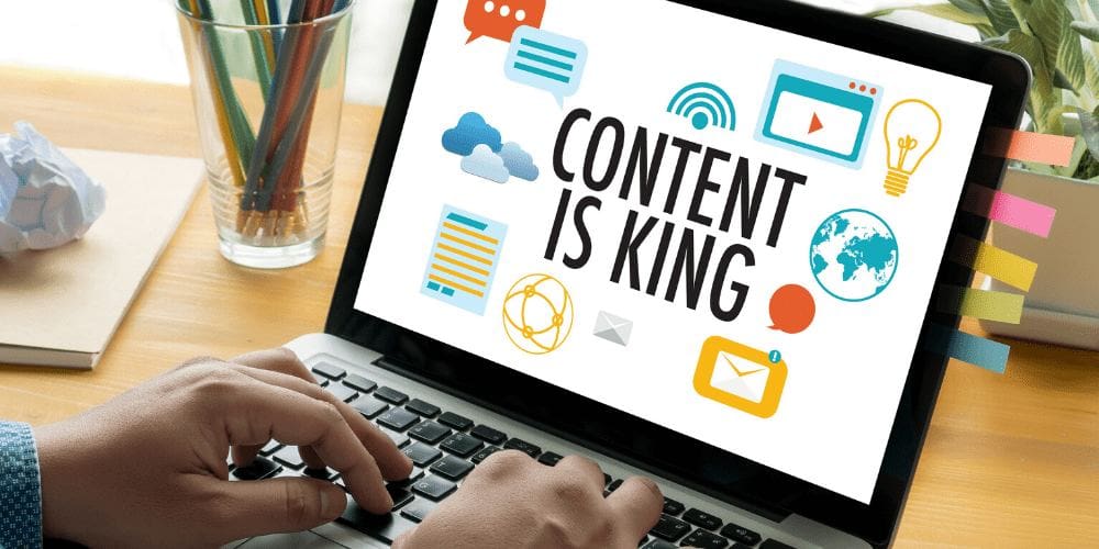 a person typing on a laptop with the words content is king.