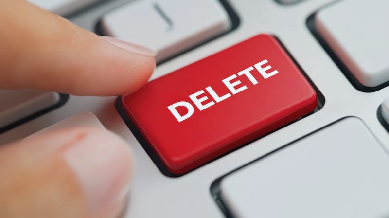 A finger is about to press a large red "DELETE" key on a computer keyboard, symbolizing the action of deleting or removing something digitally—such as choosing to delete a Google business listing.