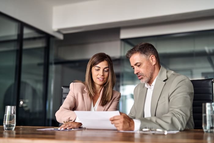 Two reputation management consultants sitting at a table looking at papers.